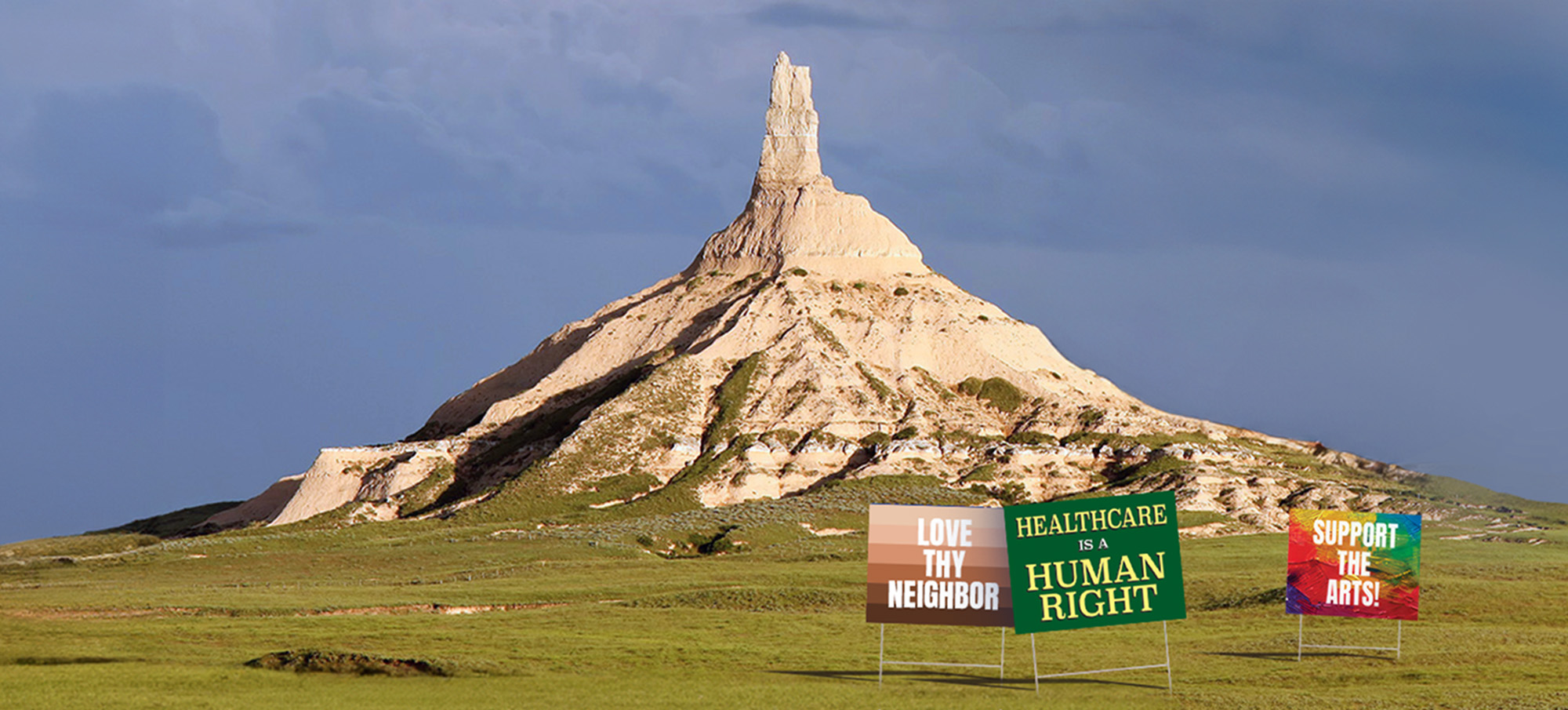Chimney Rock in Nebraska with yard signs celebrating "Love They Neighbor," "Healthcare is a Human Right" and "Support the Arts"